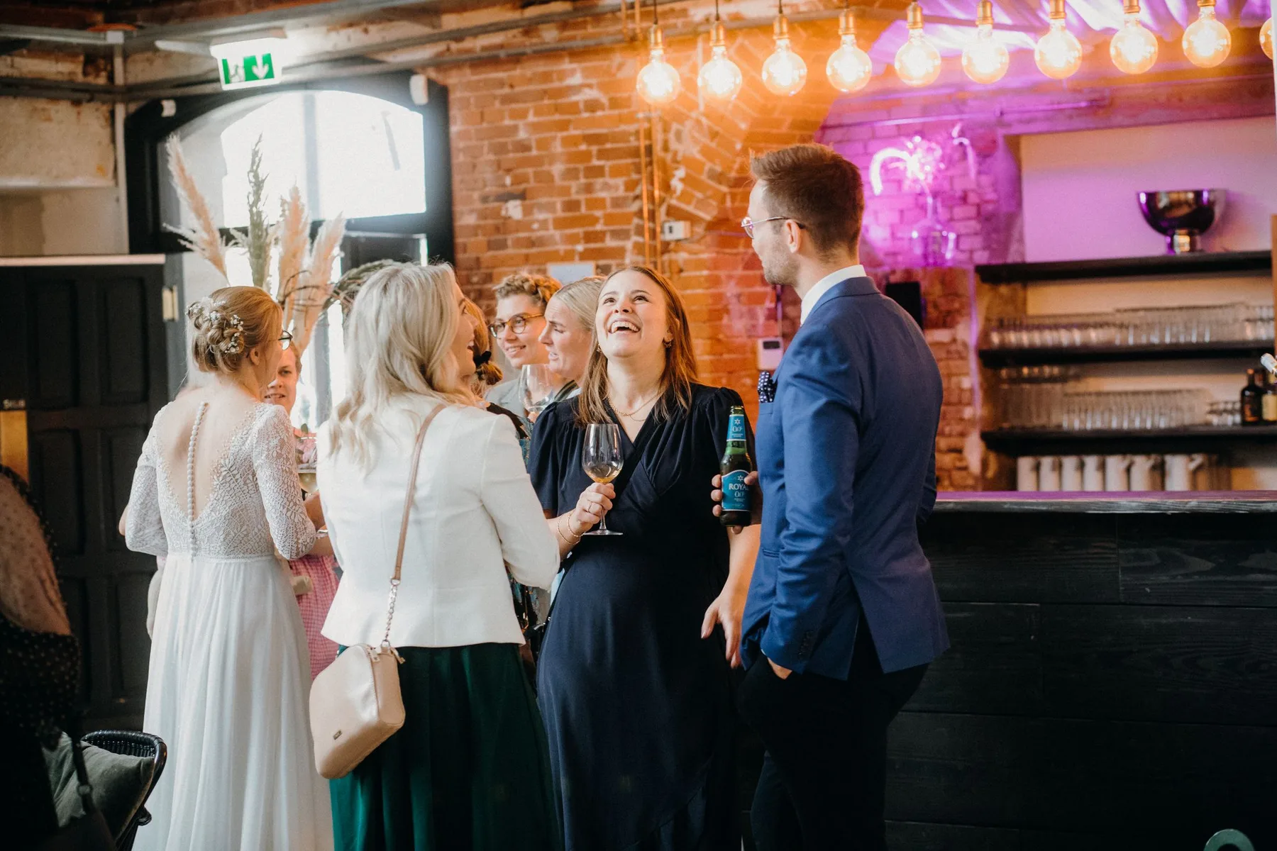 A small group of guests talking at a bar under warm lights