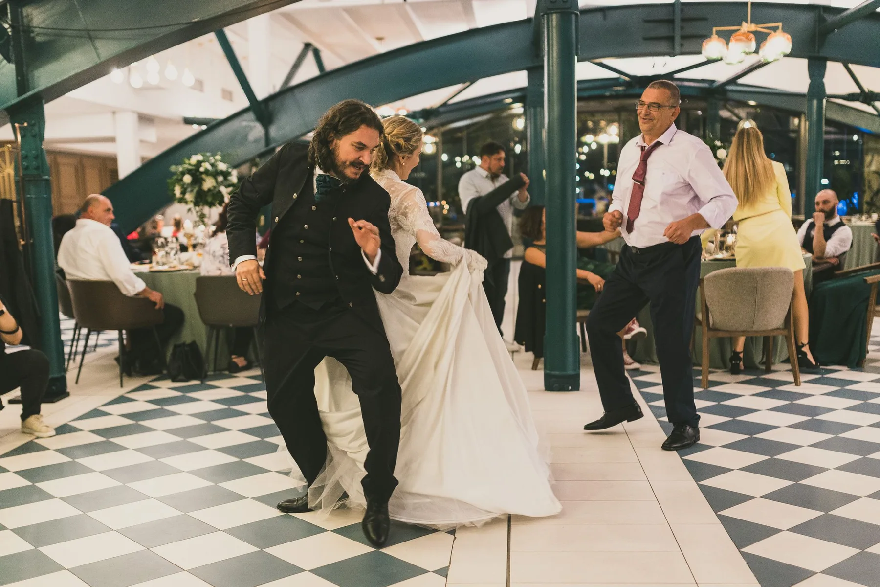 The couple dancing on a chequered floor as a guest joins them