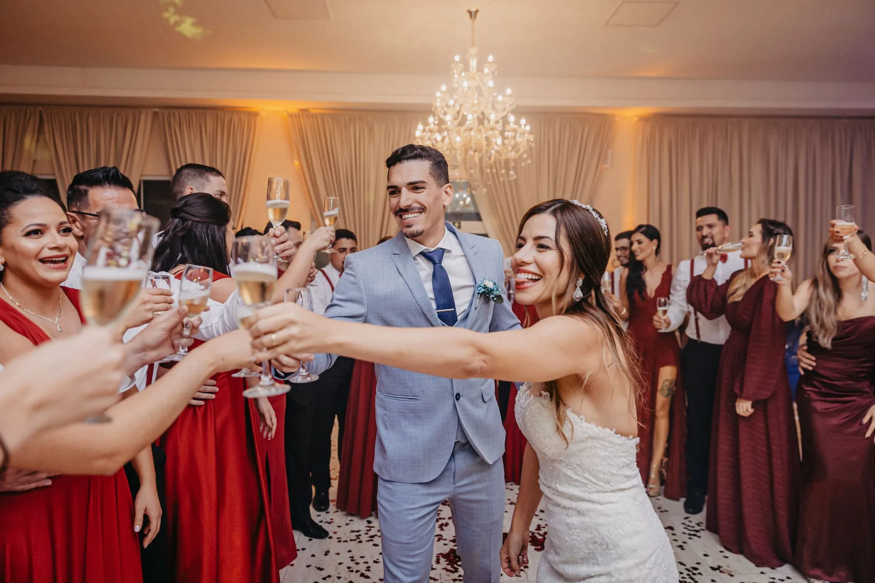 The couple in the middle of a crowd of guests, everyone raising a glass
