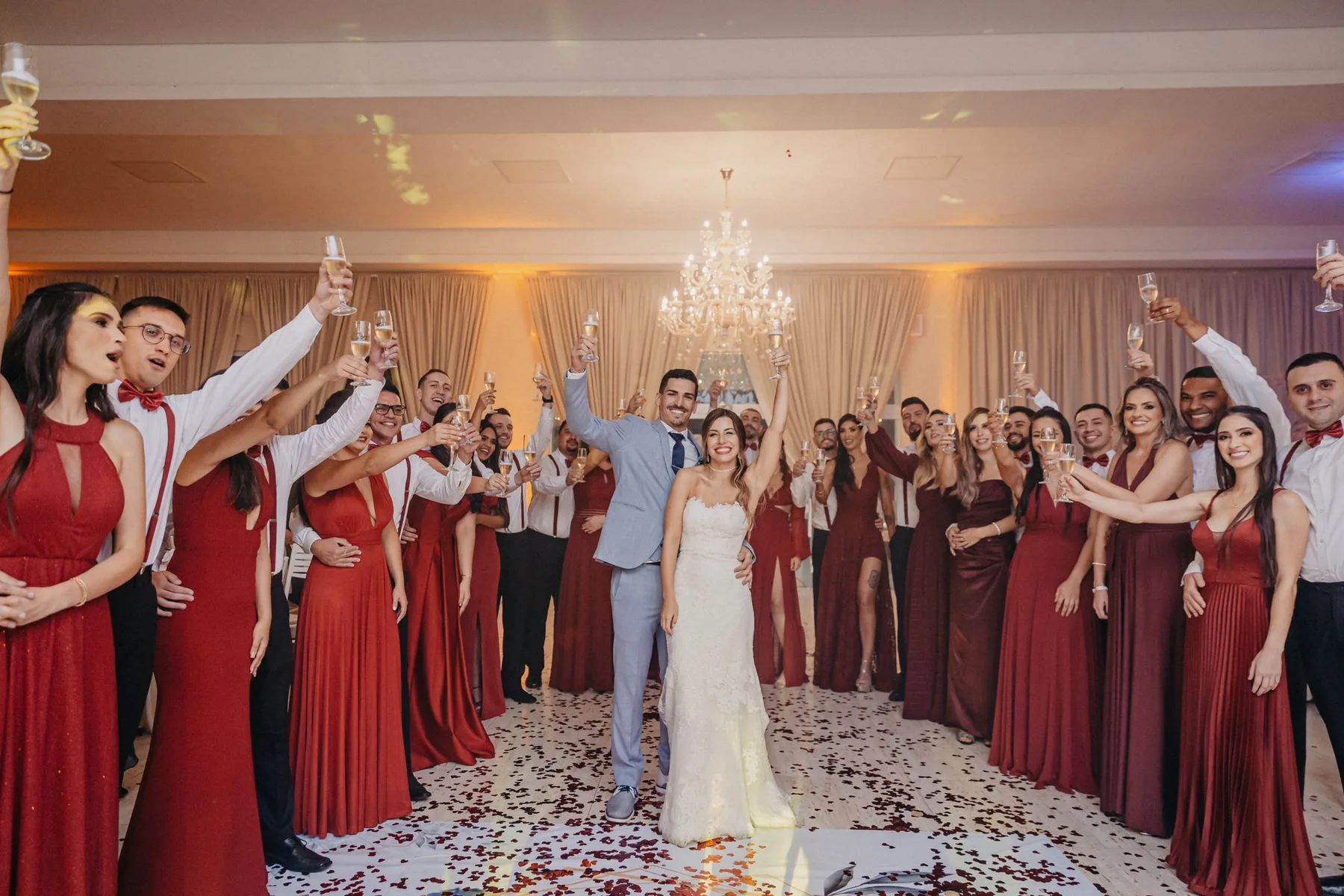 The couple standing in the middle of their wedding party, everyone raising a glass