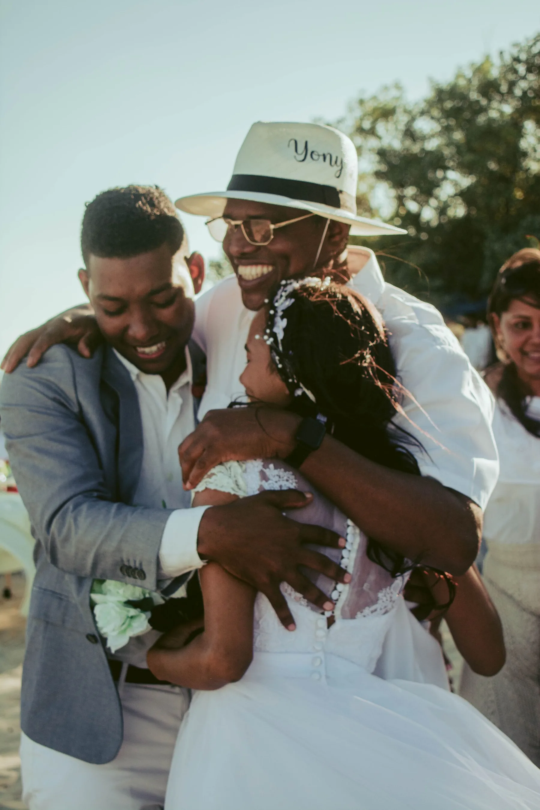 Three people holding each other in a long embrace outdoors