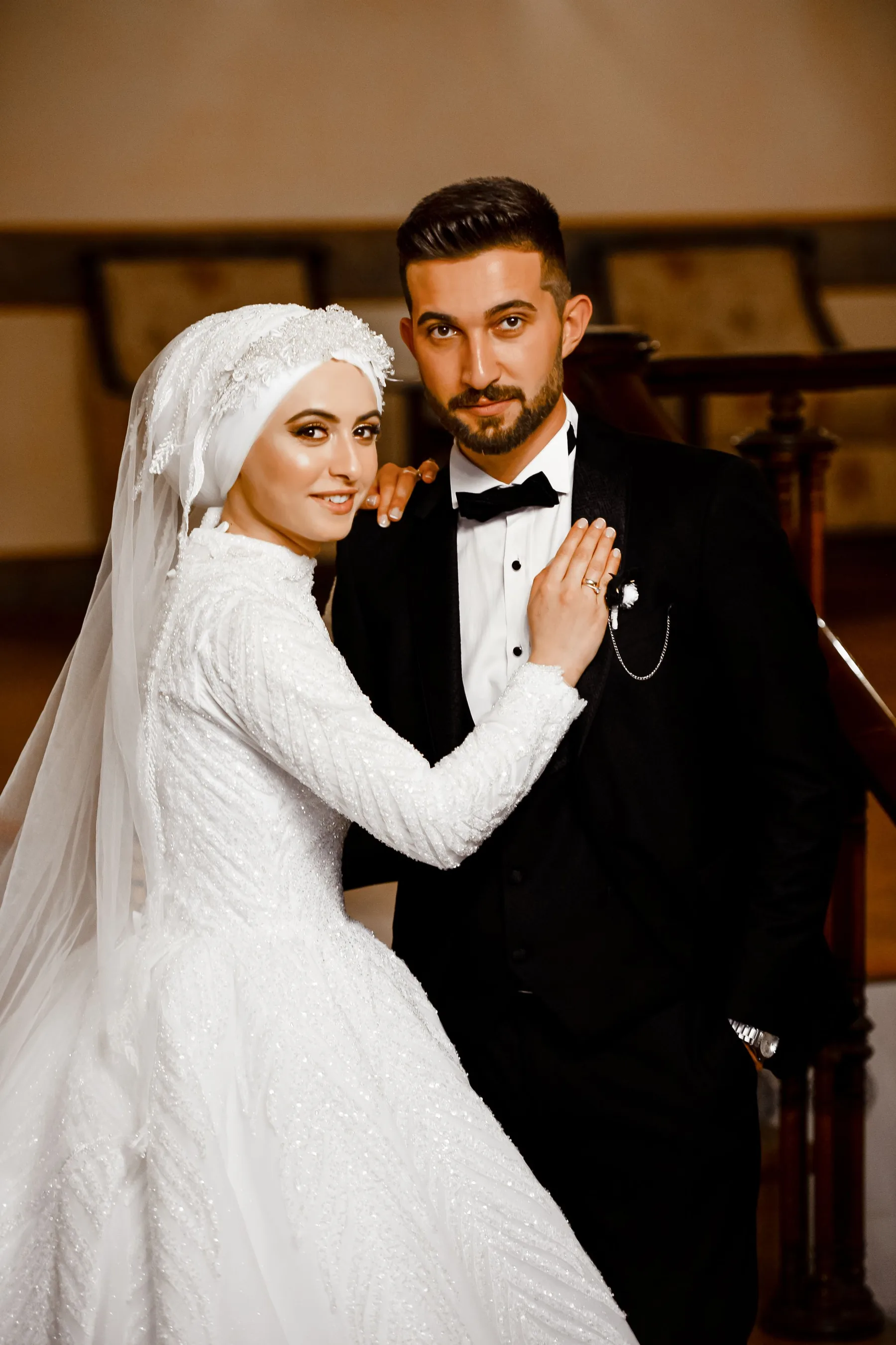 The couple standing together at the foot of a staircase