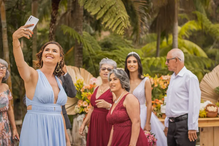A guest holding up her phone to take a selfie at an outdoor ceremony